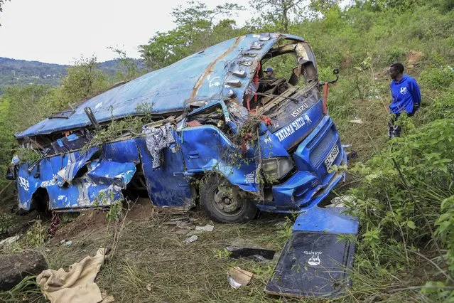 A man observes the wreckage at the scene of a bus crash involving dozens of mourners who were returning from a funeral, near Mwatate, in southern Kenya Sunday, April 16, 2023. At least 10 people died when the bus they were traveling in left the road and rolled several times in southern Kenya, police said Sunday. (Photo by AP Photo)