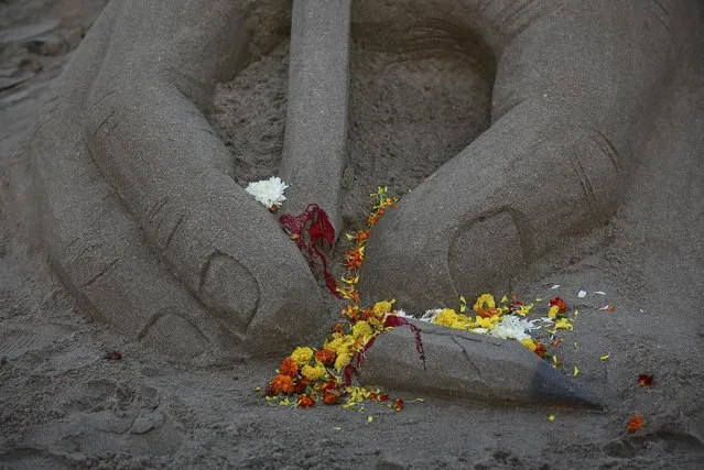 Flowers are seen scattered on a broken pencil sand sculpture made by an artist in tribute to the victims of a shooting by gunmen at the offices of French satirical weekly Charlie Hebdo, at a beach in Mumbai January 9, 2015. (Photo by Danish Siddiqui/Reuters)