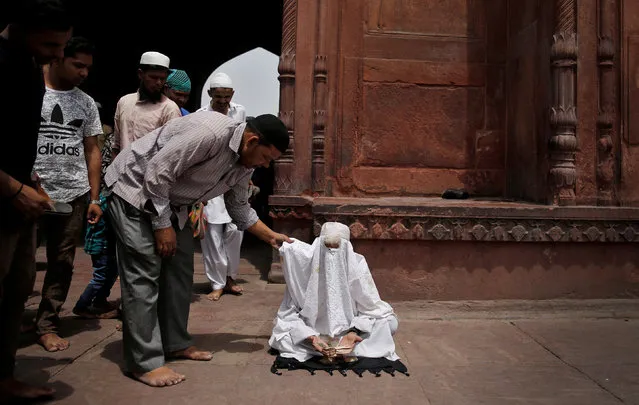 A man begging for money while posing as a woman is confronted inside Jama Masjid (Grand Mosque) on the second day of Ramadan in the old quarters of Delhi, India, May 18, 2018. (Photo by Cathal McNaughton/Reuters)