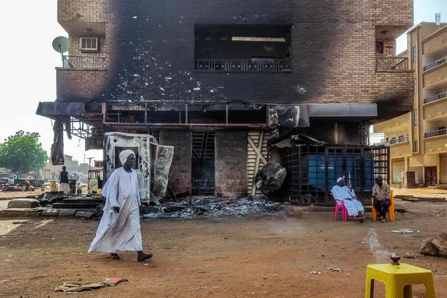 A man walks past a burnt out bank branch in southern Khartoum on May 24, 2023. Sporadic artillery fire still echoed in Sudan's capital on May 24 but residents said fighting had calmed following a US and Saudi-brokered ceasefire, raising faint hopes in the embattled city. (Photo by AFP Photo/Stringer)