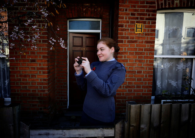 A woman takes a picture of a Remembrance Sunday parade through Fulham in West London, Britain November 11, 2012. (Photo by Kevin Coombs/Reuters)