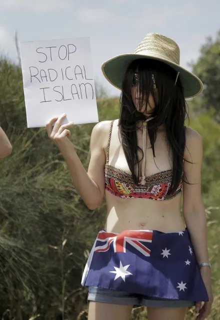 A bikini-clad protester wearing an Australian flag as a skirt holds a sign reading “Stop radical Islam” during a rally on the 10th anniversary of race riots in Sydney's beachside suburb of Cronulla, December 12, 2015. (Photo by Jason Reed/Reuters)