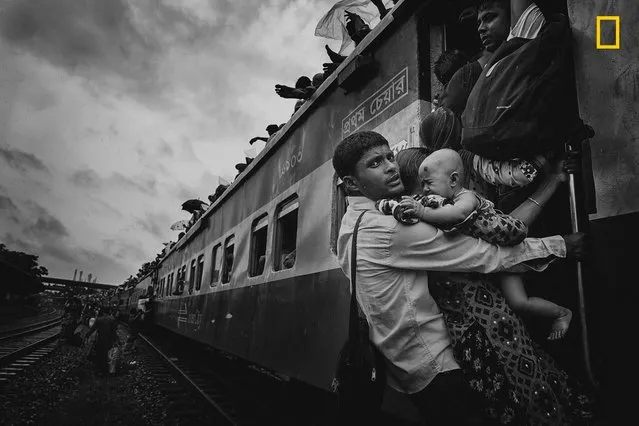 Third Place Winner, People: Challenging journey. “This photograph was taken from Dhaka's airport rail station during the Eid vacation. People were returning to their village homes to spend Eid with families, and the rush at the last hour was immense. One man caught my attention: he was dangling on a train's handle with his family, trying to get inside the train. At that time, rain started and the train began to slowly move. The family had tickets to board the train, but couldnÕt get to their seats. There are many people like him, who come to Dhaka for work – leaving their families and home villages – so when they get vacation, they don't want to miss the opportunity to spend time with dear ones, no matter what”. (Photo by MD Tanveer Hassan Rohan/National Geographic Travel Photographer of the Year Contest)