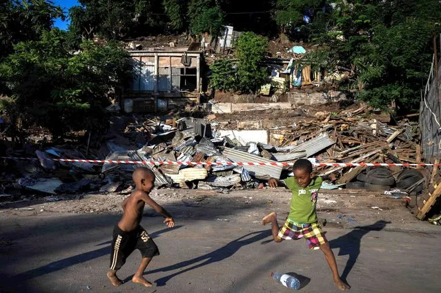 Children play football with a plastic bottle in front of demolished buildings in the shantytown of “Talus 2” district in Koungou, during its dismantling as part of Operation Wuambushu on the French Indian Ocean island of Mayotte, on May 23, 2023. Police and bulldozers moved in to clear a slum on the French Indian Ocean island of Mayotte on May 22, marking the start of a long-promised operation against substandard housing and illegal migration. Since April, France has deployed hundreds of police officers in Mayotte – the country's poorest region – to prepare for a slum-clearing initiative called Operation Wuambushu (“Take Back” in the local language). (Photo by Philippe Lopez/AFP Photo)