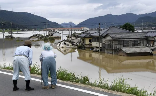 Residents look at half submerged houses in floodwater from heavy rains, in Kurashiki, Okayama prefecture, southwestern Japan, Sunday, July 8, 2018. Heavy rainfall hammered southern Japan for the third day, prompting new disaster warnings on Kyushu and Shikoku islands Sunday. (Photo by Koji Harada/Kyodo News via AP Photo)