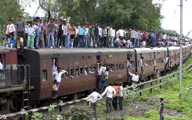 Indian devotees travel atop of a crowded train as they head to attend the Dada Ji Dham fair which coincides with the Guru Purnima festival at Khandwa, Madhya Pradesh state, India, Monday, July 22, 2013. The festival that falls on a full moon day is observed by Hindus and Buddhists, and marked by ritualistic veneration of the Guru, or the teacher. (Photo by AP Photo)