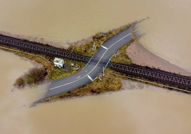 A rail road crossing is surrounded by flooding caused by rain and melting snow in Nidderau near Frankfurt, Germany, Wednesday, February 3, 2021. (Photo by Michael Probst/AP Photo)