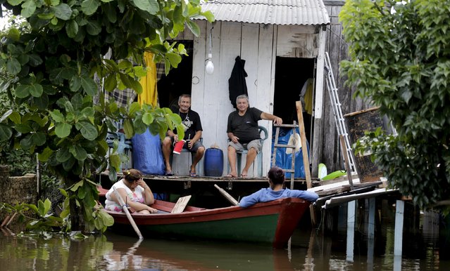 A family (top) sits in their house above flood waters in Asuncion, December 27, 2015. (Photo by Jorge Adorno/Reuters)