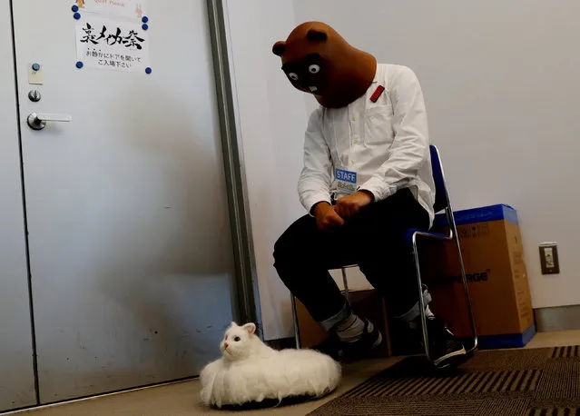 A man wearing Itachiguma mask looks at robot cat Ballon, which moves on the floor, at its photo opportunity during the Underground Maker Festival in Tokyo, Japan August 5, 2018. According to Japanese artist Daiki Sako who created the robot by combining a robot cleaner and body and head of a cat which made by handicraft, the robot was inspired by the video artworks “Welcome to Kitty City” by Cyriak. (Photo by Kim Kyung-Hoon/Reuters)