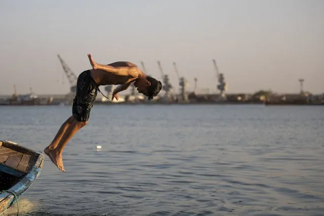 A boy dives in the Shatt al-Arab waterway in the southern Iraqi city of Basra, on July 17, 2023 as an extreme heatwave hits the region. (Photo by Hussein Faleh/AFP Photo)
