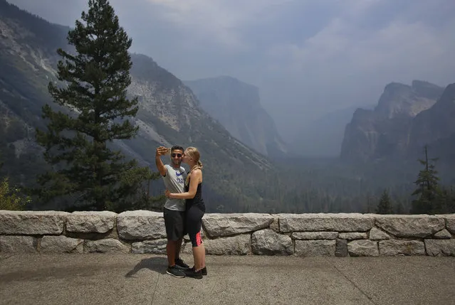 Ann-Cathrin Riepe take in a moment for a photo even though the famed Tunnel View vista in Yosemite National Park is blocked by a smoke screen from existing fires as the park reopened after a three week closure from smoke and fires that led to most tourists canceling their trips, Tuesday, August 14, 2018 in Yosemite, Calif. (Photo by Gary Kazanjian/AP Photo)