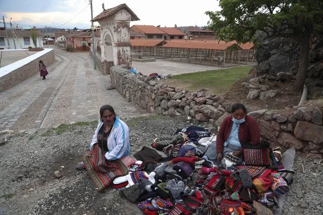Women selling traditional clothing from the Andes wait for buyers outside of closed market amid the COVID-19 pandemic in Chincheros, Peru, Monday, October 26, 2020. Cuzco, the historic capital of the Inca empire near Machu Picchu lives almost entirely from international tourism and is suffering the worst crisis in its recent history. (Photo by Martin Mejia/AP Photo)