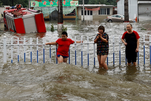 People stand by a rail amid floodwaters after the rains and floods brought by remnants of Typhoon Doksuri, in Zhuozhou, Hebei province, China on August 3, 2023. (Photo by Tingshu Wang/Reuters)