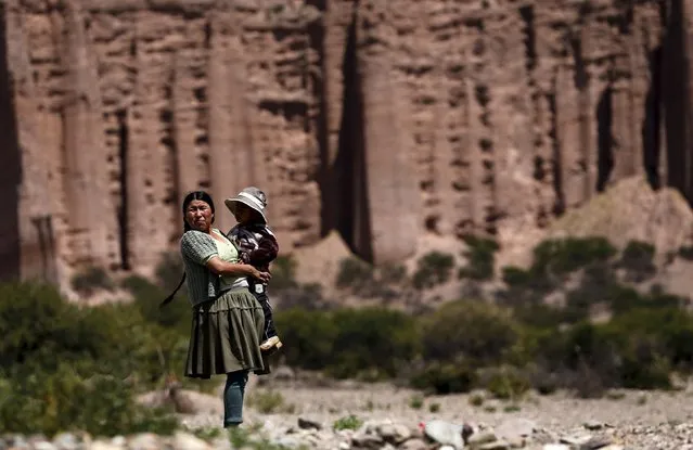 An Aymara woman holds a child as she stands on the side of the road to watch vehicles in the fifth stage Jujuy-Uyuni in the Dakar Rally 2016 near Uyuni, Bolivia, January 7, 2016. (Photo by Marcos Brindicci/Reuters)