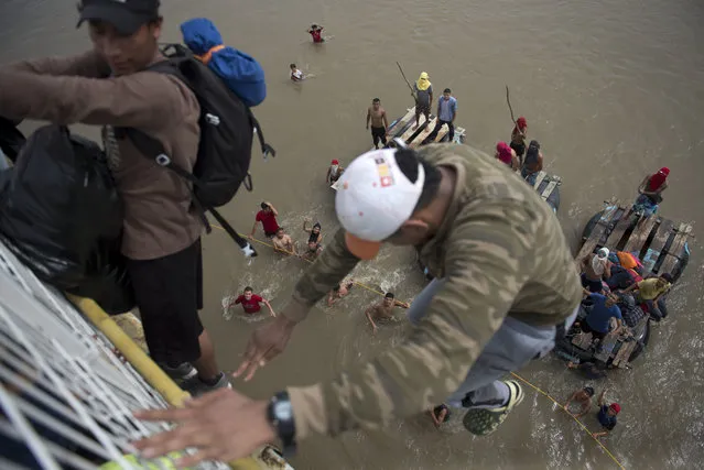 Migrants tired of waiting to cross into Mexico, jumped from a border bridge fence into the Suchiate River, in Tecun Uman, Guatemala, Friday, October 19, 2018. Some of the migrants traveling in a mass caravan towards the U.S.-Mexico border organized a rope brigade to ford its muddy waters. (Phptp by Oliver de Ros/AP Photo)
