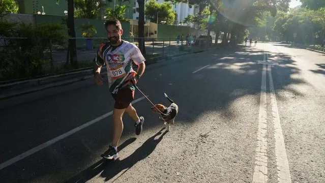 A man runs with his dog as people and their dogs attend a race to support Venezuelan shelters for animals, in Caracas, Venezuela on July 30, 2023. (Photo by Efrain Otero/Reuters)