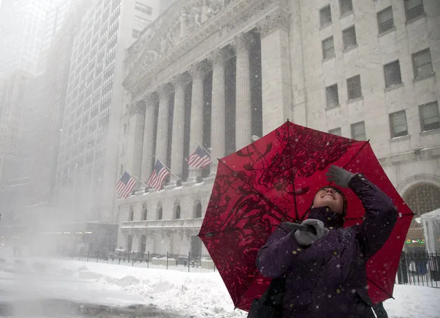 Jessica Ourisman, a travel advisor from Baltimore, looks up at the buildings around the New York Stock Exchange while touring lower Manhattan with a group of other advisors during a snow storm, Saturday, January 23, 2016, in New York. (Photo by Julie Jacobson/AP Photo)