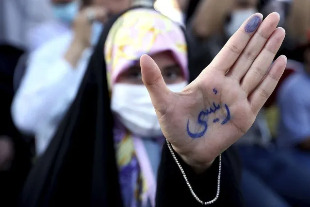 A supporter of presidential candidate Ebrahim Raisi shows her hand with writing in Persian that reads “Raisi”, during a rally in Tehran, Iran, Wednesday, June 16, 2021. Iran's clerical vetting committee has allowed just seven candidates for the Friday, June 18, ballot, nixing prominent reformists and key allies of President Hassan Rouhani. The presumed front-runner has become Ebrahim Raisi, the country's hard-line judiciary chief who is closely aligned with Supreme Leader Ayatollah Ali Khamenei. (Photo by Ebrahim Noroozi/AP Photo)