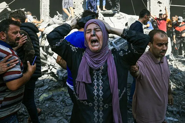 A Palestinian woman reacts as others rush to look for victims in the rubble of a building following an Israeli strike in Khan Yunis in the southern Gaza Strip on October 17, 2023, amid the ongoing battles between Israel and the Palestinian group Hamas. Thousands of people, both Israeli and Palestinians have died since October 7, 2023, after Palestinian Hamas militants based in the Gaza Strip, entered southern Israel in a surprise attack leading Israel to declare war on Hamas in Gaza on October 8. (Photo by Mahmud Hams/AFP Photo)
