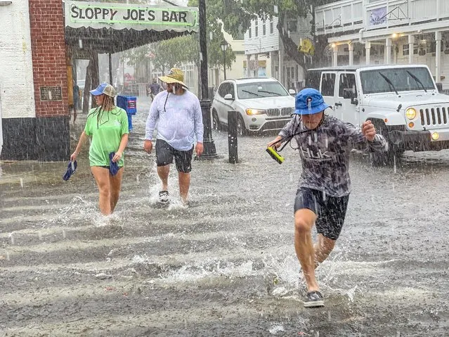 Pedestrians dash across the intersection of Greene and Duval streets as heavy winds and rain associated with Tropical Storm Elsa passes Key West, Fla., on Tuesday, July 6, 2021. The weather was getting worse in southern Florida on Tuesday morning as Tropical Storm Elsa began lashing the Florida Keys, complicating the search for survivors in the condo collapse and prompting a hurricane watch for the peninsula's upper Gulf Coast. (Photo by Rob O'Neal/The Key West Citizen via AP Photo)