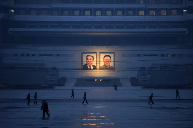 This photo taken on December 3, 2018 shows pedestrians walking past the portraits of late North Korean leaders Kim Il Sung and Kim Jong Il across Kim Il Sung square in Pyongyang. (Photo by Ed Jones/AFP Photo)