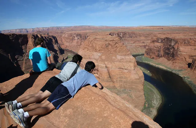 People lie on the edge of a cliff to view the Colorado River at Horseshoe Bend on March 30, 2015 in Page, Arizona. As severe drought grips parts of the Western United States, a below average flow of water is expected to flow through the Colorado River Basin into two of its biggest reservoirs, Lake Powell and Lake Mead. Lake Powell is currently at 45 percent of capacity and is at risk of seeing its surface elevation fall below 1,075 feet above sea level by September, which would be the lowest level on record. (Photo by Justin Sullivan/Getty Images)