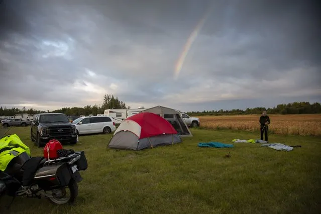 Craig Yeo, an evacuee from Yellowknife, territorial capital of the Northwest Territories, packs up his tent under a rainbow at a free campsite provided by the community in High Level, Alta., Thursday, August 18, 2023.  (Photo by Bill Braden/The Canadian Press via AP Photo)