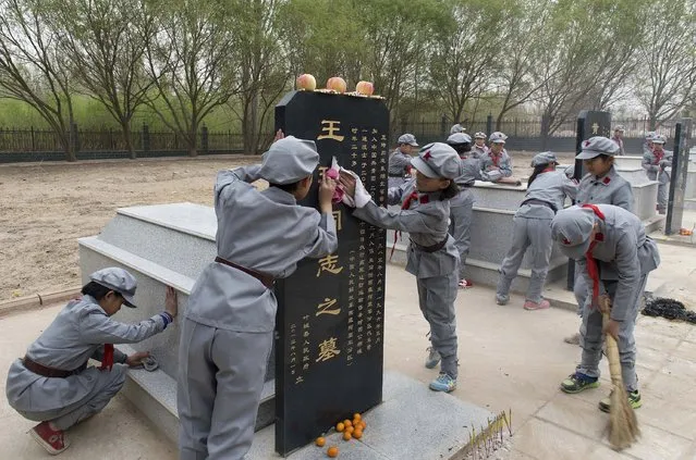 Primary school students in Red Army uniforms clean tombs at a Martyrs' Cemetery ahead of the Qingming Festival, or Tomb Sweeping Festival, in Yecheng, Xinjiang Autonomous Region, April 4, 2015. (Photo by Reuters/Stringer)