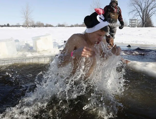 A participant reacts after jumping into a hole cut in the ice on the Ottawa River during the annual Great Canadian Chill polar bear dip in Ottawa January 1, 2014. (Photo by Chris Wattie/Reuters)