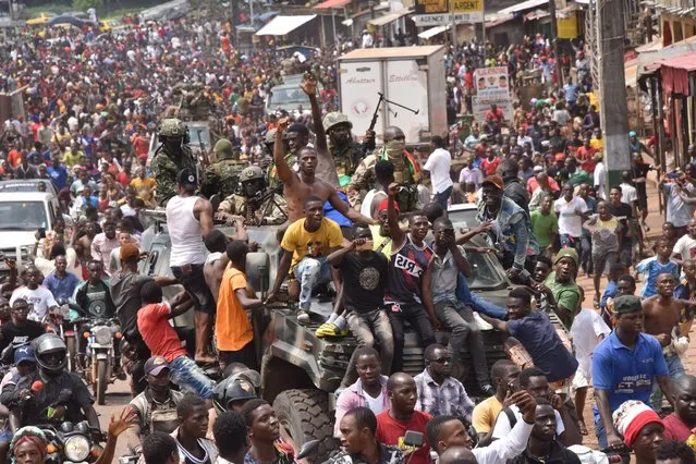 People celebrate in the streets with members of Guinea's armed forces after the arrest of Guinea's president, Alpha Conde, in a coup d'etat in Conakry, September 5, 2021. Guinean special forces seized power in a coup on September 5, arresting the president and imposing an indefinite curfew in the poor west African country. “We have decided, after having taken the president, to dissolve the constitution”, said a uniformed officer flanked by soldiers toting assault rifles in a video sent to AFP. (Photo by Cellou Binani/AFP Photo)
