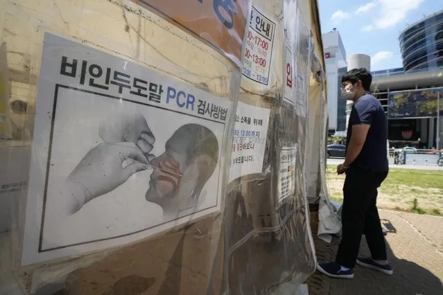 A man waits to get coronavirus testing at a makeshift testing site in Seoul, South Korea, Friday, July 16, 2021. South Korean officials are pushing for tightened pandemic restrictions beyond the hard-hit capital area as they wrestle with a record-breaking surge in coronavirus cases. The signs on a banner at left read “How to check Polymerase Chain Reaction”. (Photo by Ahn Young-joon/AP Photo)