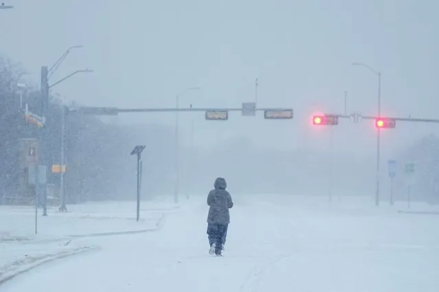 A jogger trots on a snow-covered road during a winter storm, Monday, January 15, 2024, in Grand Prairie, Texas. (Photo by Julio Cortez/AP Photo)