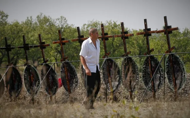 A local man walks during a funeral ceremony of 30 civilians, who were exhumed from a mass grave a week ago near Irmino village not far from Pervomaysk in self-proclaimed Lugansk People's Republic, Ukraine, 31 August 2021. Locals gathered for a reburial ceremony for the remains of 30 unidentified civilian victims who were lost and buried in an improvised grave during fighting between pro-Russian militants and Ukrainian forces during the Eastern-Ukrainian conflict in 2014. (Photo by Alexander Usenko/EPA/EFE)
