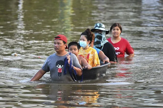 Thai people wade through floodwaters in Chaiyaphum province, northeast of Bangkok, Thailand, Tuesday, September 28, 2021. Thai disaster officials say flooding caused by seasonal monsoon rains have affected more than 71,000 households in 30 provinces and killed six people since the weekend. (Photo by Thanachote Thanawikran/AP Photo)