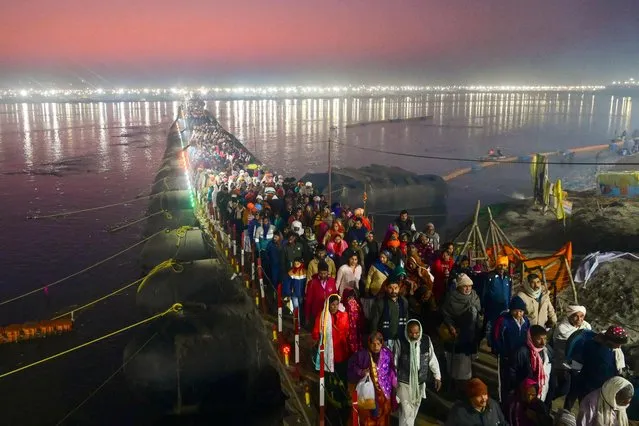 Hindu devotees cross a pontoon bridge as they arrive to take a holy dip at the “Sangam” the confluence of the rivers Ganges, Yamuna and mythical Saraswati, on the auspicious bathing day of “Mauni Amavasya” during the annual religious “Magh Mela” festival in Prayagraj on February 9, 2024. (Photo by Sanjay Kanojia/AFP Photo)