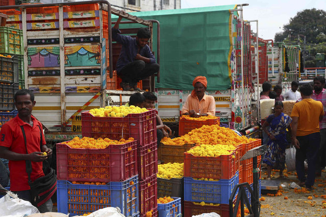 Marigold flower vendors wait for customers at a wholesale market ahead of Diwali, the festival of lights, in Hyderabad, India, Wednesday, November 3, 2021. Marigold flowers are used as offerings to Hindu deities as well as for decorative purposes during festivals. (Photo by Mahesh Kumar A./AP Photo)