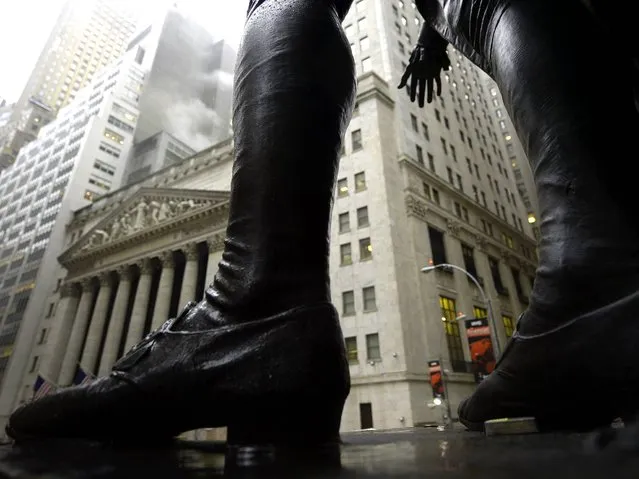 Rain falls with the New York Stock Exchange in the background as seen through the statue of George Washington at Federal Hall in Manhattan, on February 19, 2014. (Photo by Timothy Clary/AFP Photo)