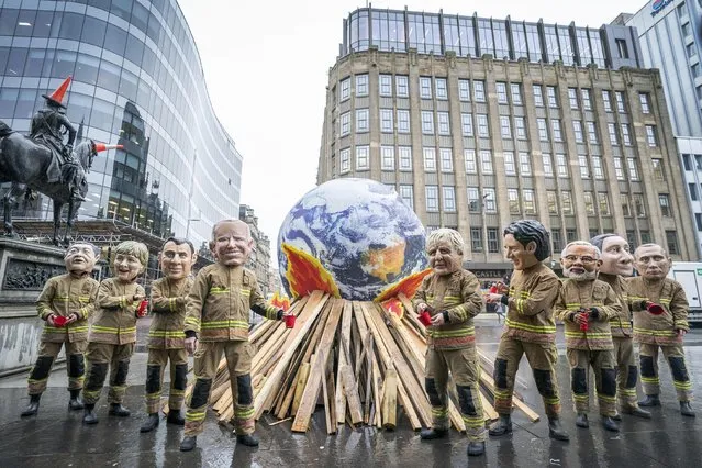Campaigners wearing “big heads” of world leaders, including Boris Johnson, Joe Biden, Justin Trudeau and Narendra Modi gather for Oxfam's “Ineffective Fire-Fighting World Leaders” protest performance in front of a 10 foot globe with a simulated bonfire, during the official final day of the Cop26 summit in Glasgow on Friday, November 12, 2021. (Photo by Jane Barlow/PA Images via Getty Images)