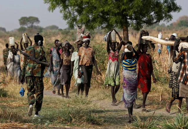 A soldier walks past women carrying their belongings near Bentiu, northern South Sudan, February 11, 2017. (Photo by Siegfried Modola/Reuters)