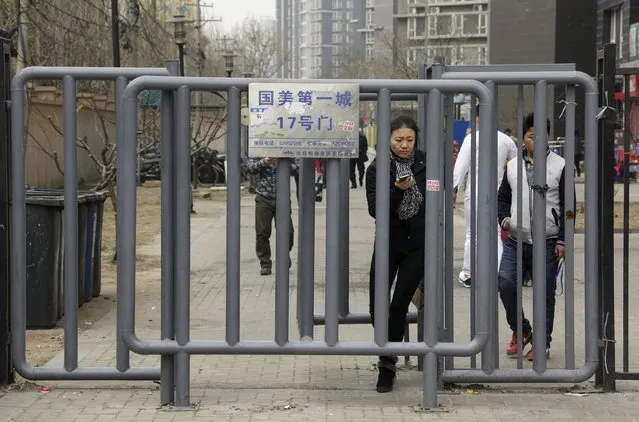 Residents walk out through a fence at the entrance of a residential community in Beijing, China, March 22, 2016. (Photo by Jason Lee/Reuters)