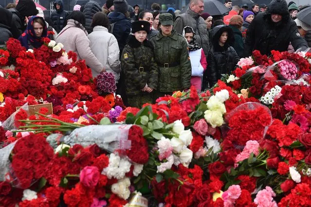 People lay flowers at a makeshift memorial in front of the Crocus City Hall in Krasnogorsk on March 24, 2024, as Russia observes a national day of mourning after a massacre that killed more than 130 people. (Photo by Olga Maltseva/AFP Photo)