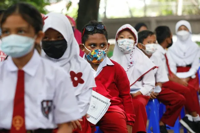 Students wearing protective face masks sit while waiting to receive their dose of the vaccine against the coronavirus disease (COVID-19), during a vaccination program for children aged 6-11 years, in Jakarta, Indonesia, December 14, 2021. (Photo by Ajeng Dinar Ulfiana/Reuters)