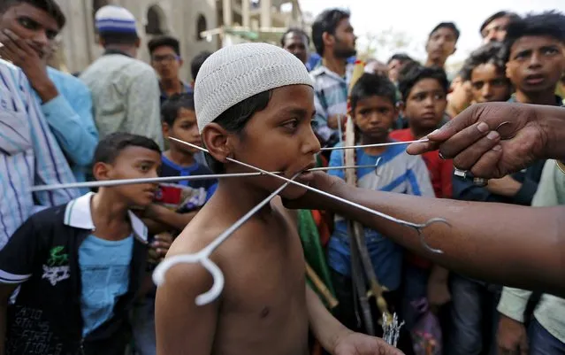 The mouth of a Muslim boy is pierced with metal skewers during an annual religious procession to mark the death anniversary of a local Sufi saint Mahmood Shah Bukhari in Ahmedabad, India, April 13, 2016. (Photo by Amit Dave/Reuters)