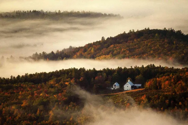 Valley fog wafts through the autumn-colored hills near the Picket Hill Farm, Wednesday morning, October 13, 2021, in Denmark, Maine. The farm complex was built in the 1830s. (Photo by Robert F. Bukaty/AP Photo)
