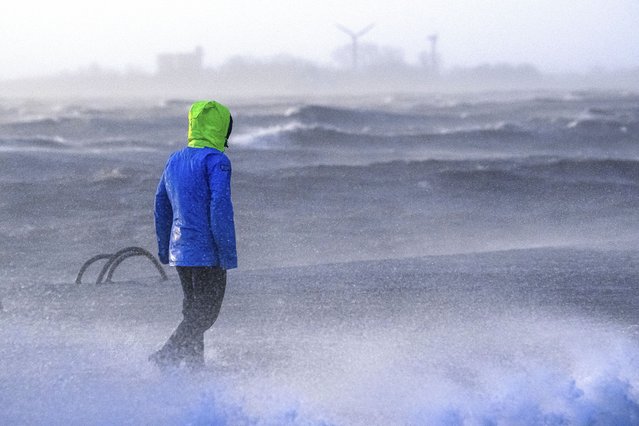 A person walks along the banks of the Weser estuary during a storm surge and waves in Bremerhaven, Germany, Friday December 22, 2023. Pre-Christmas rail travelers in parts of Germany faced widespread disruption on Friday as a storm swept across northern Europe, bringing down trees and prompting warnings of flooding on the North Sea coast. (Photo by Sina Schuldt/dpa via AP Photo)