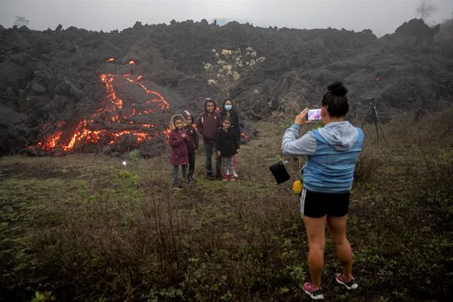 Family members pose for photos near lava flowing from Pacaya Volcano near El Patrocinio village in San Vicente Pacaya, Guatemala, Friday, April 16, 2021. (Photo by Moises Castillo/AP Photo)