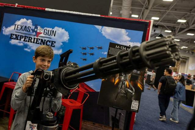 A child poses with a machine gun at an exhibition booth during the National Rifle Association (NRA) annual convention in Dallas, Texas, U.S., May 18, 2024. (Photo by Carlos Barria/Reuters)