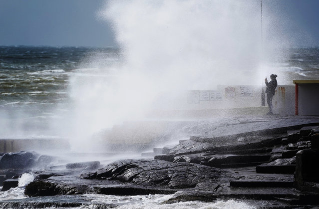A man takes photos of the waves at Blackrock Diving Board, Salthill, Co. Galway on April 6, 2024. Thousands of customers have been left without electricity as Storm Kathleen continues to sweep across the island of Ireland. (Photo by Brian Lawless/PA Images via Getty Images)