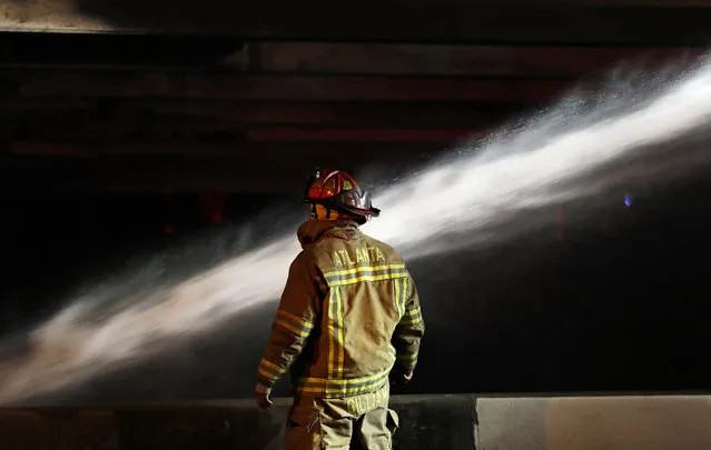 A firefighter surveys the section of an overpass that collapsed from a large fire on Interstate 85 in Atlanta, Thursday, March 30, 2017. Atlanta officials say a massive fire that burned for more than an hour caused the collapse of the interstate overpass. Georgia Gov. Nathan Deal has issued a state of emergency for the county. (Photo by David Goldman/AP Photo)