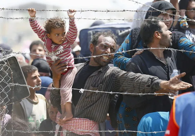 A Syrian refugee reacts as he waits behind border fences to cross into Turkey at Akcakale border gate in Sanliurfa province, Turkey, June 15, 2015. (Photo by Umit Bektas/Reuters)
